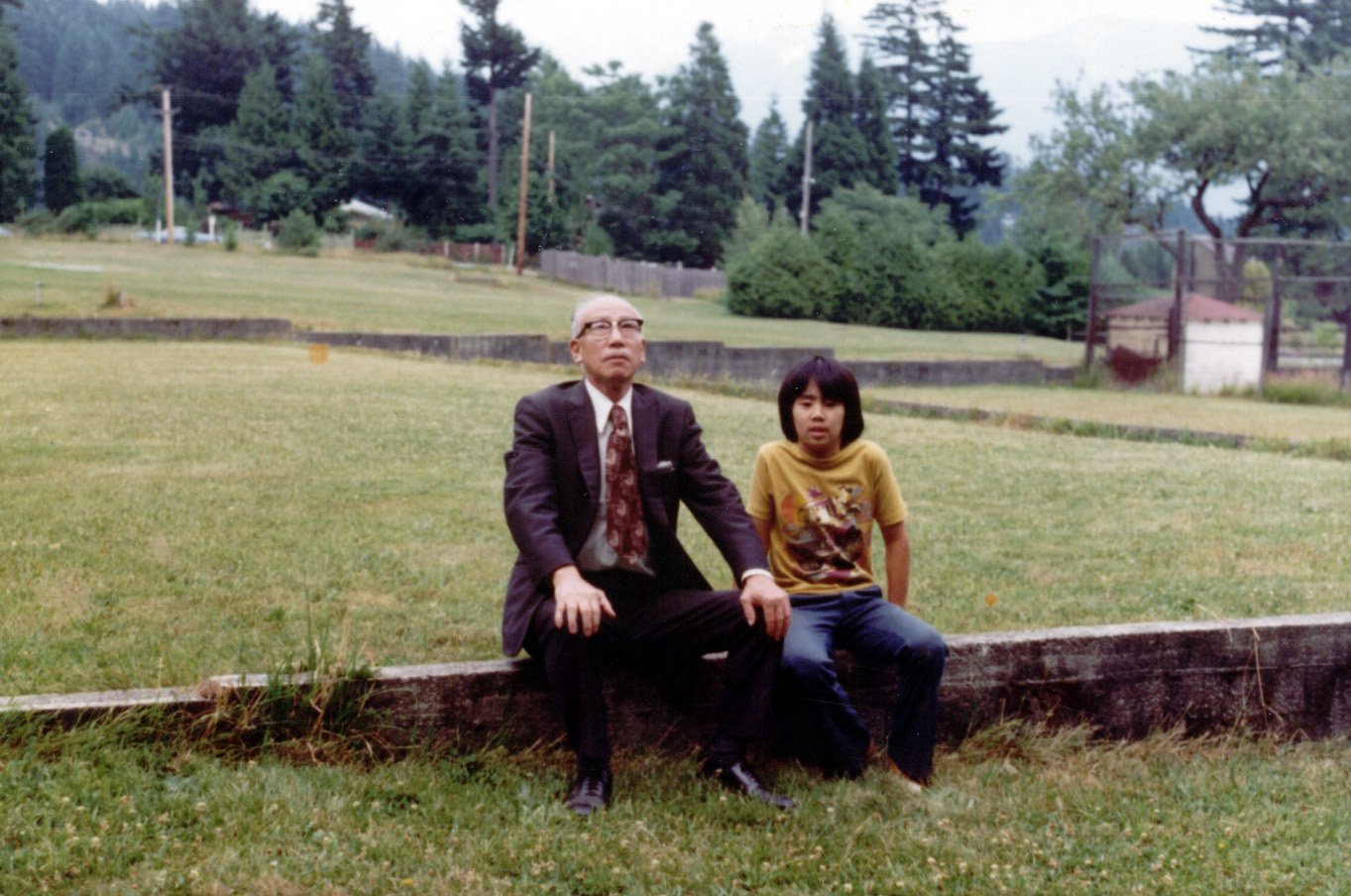 BIM&amp;A Object ID# 1551 
Mr. Keido Uemon Koga (son of Daikichi Koga the USSC foreman) and his grandson seated on part of remaining foundation of old Union Steamship Hotel. 1975