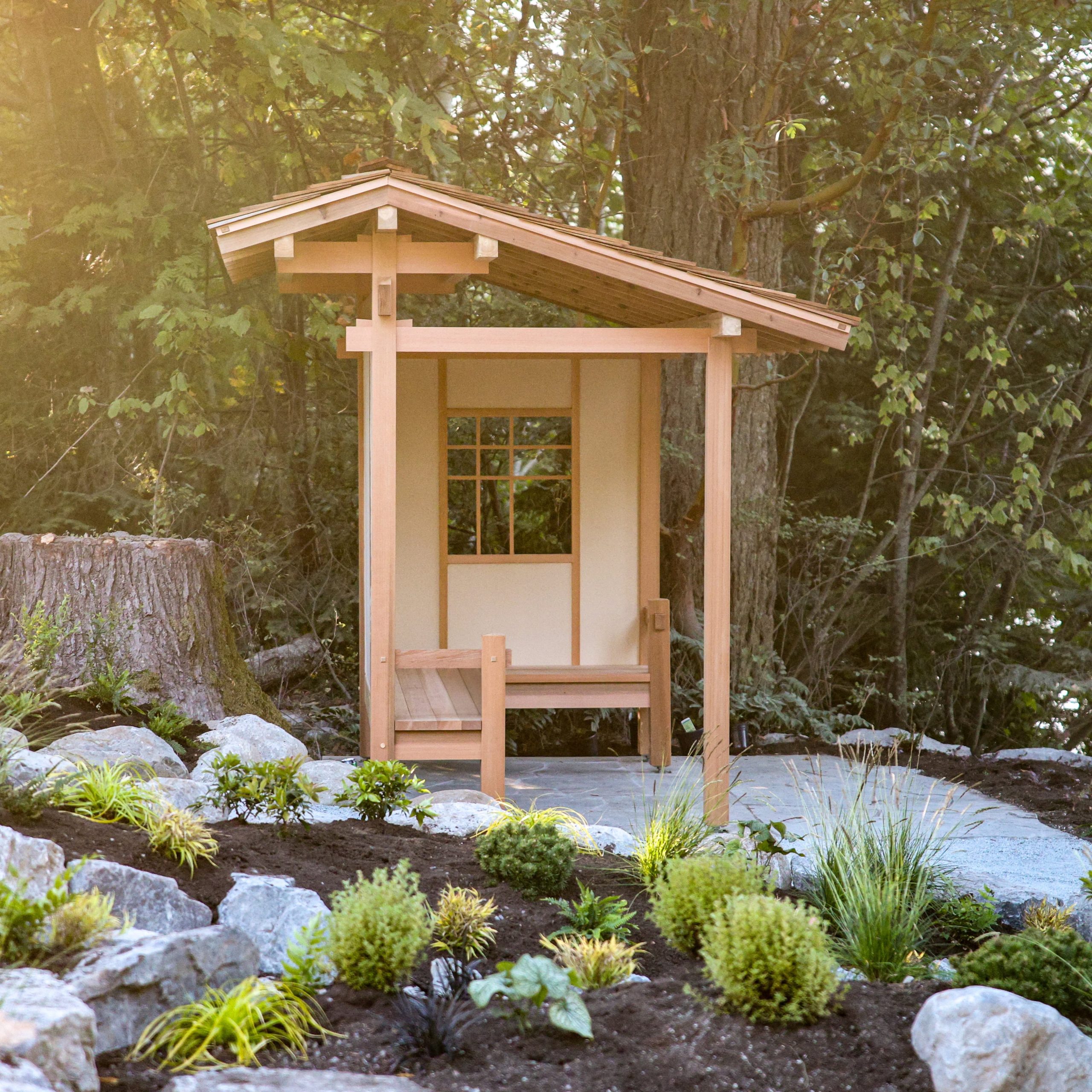 A small light coloured wooden building in a garden